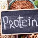 small chalk board with the word "protein" written on it sitting on top of various sources of protein